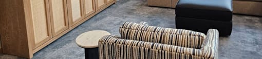 A living room with a striped chair and a couch.