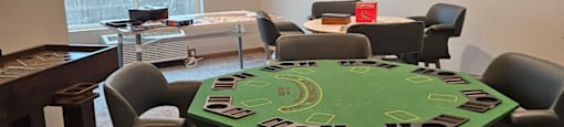 A poker table surrounded by chairs in a room.