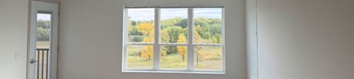 A room with a large window overlooking a field.