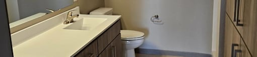 A bathroom with a toilet, sink, and mirror.