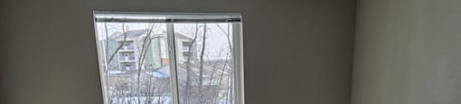 A room with a carpeted floor and a window showing a snowy scene outside.