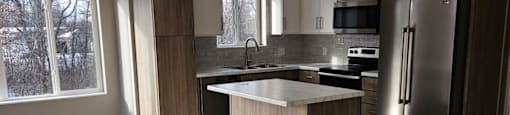 A modern kitchen with a refrigerator, sink, and cabinets.