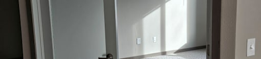 A white door is open to a room with a carpet.