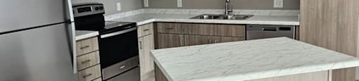 A modern kitchen with a refrigerator, microwave, oven, sink, and cabinets.