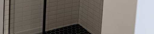 A white door with a black handle and a gold shower head.