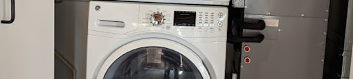 A white front load washing machine with a black control panel is stacked on top of a silver dryer.