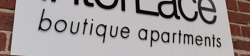 A sign for InterLace boutique apartments is displayed on a brick wall.