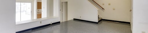 A spacious room with a staircase and a window.