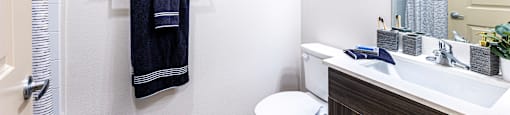 Bathroom with a toilet sink and shower and a mirror at The Parker Austin, Pflugerville, TX