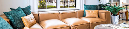 Living room with a brown couch and a large window at The Parker Austin, Pflugerville, Texas