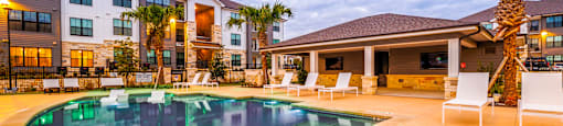 Swimming pool with chairs and a building in the background at The Parker Austin, Pflugerville, 78660