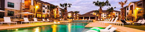 Large pool with a lounge chair in the water at an apartment complex at The Parker Austin, Pflugerville, TX, 78660