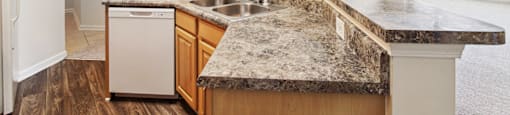 an empty kitchen with granite counter tops and a sink