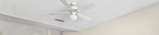an empty living room with a ceiling fan and a kitchen