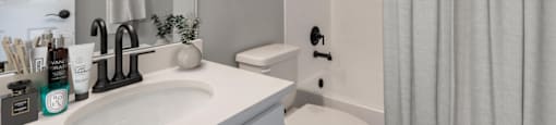 A bathroom with a white sink, toilet, and shower curtain.