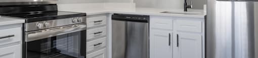 A modern kitchen with white cabinets and stainless steel appliances.