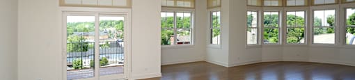 A spacious room with wooden floors and large windows.