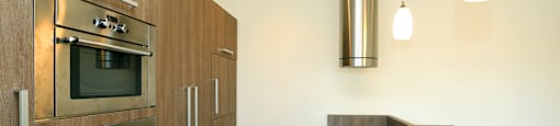 A modern kitchen with a stainless steel oven and wooden cabinets.