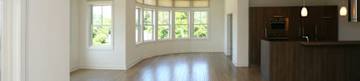 A spacious living room with wooden floors and large windows.