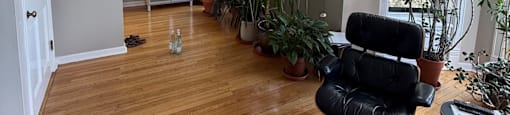 A living room with a black chair and wooden floors.
