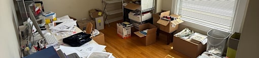 A messy room with a desk, printer, and shelves.