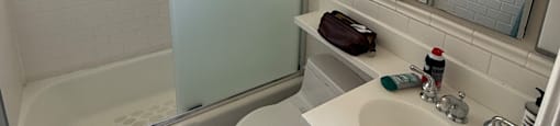 A bathroom with a toilet, sink, and mirror.