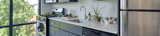 A modern kitchen with a stainless steel refrigerator and grey cabinets.