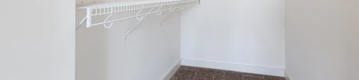 A white closet with two racks of clothes.