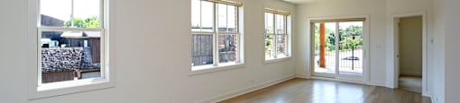 A large empty room with wooden floors and windows.