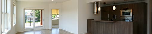 A spacious living room with wooden flooring and a television on the cabinet.