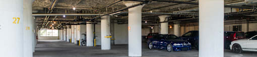 a parking garage with white pillars and cars parked in it
