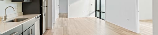 A kitchen with wooden floors and a white wall.