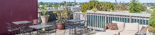 a deck with a couch and tables on a roof