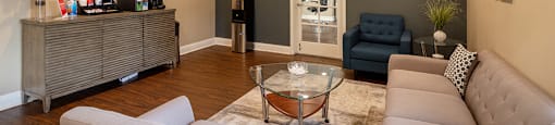 A living room with a grey couch and a glass coffee table.