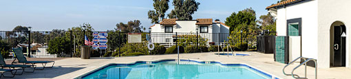 A swimming pool in a residential area with a house and trees in the background.
