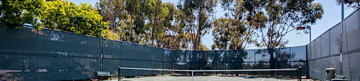 A tennis court surrounded by a fence and trees.