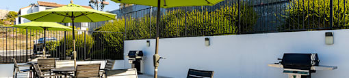 A patio with a table and chairs and a grill.