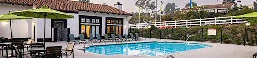 A pool with a hot tub and chairs in front of a house.