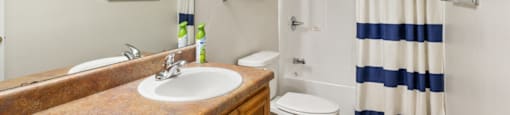 A bathroom with a sink, toilet, and striped shower curtain.