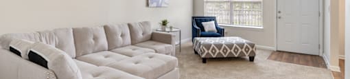 A living room with a white couch and a patterned ottoman.