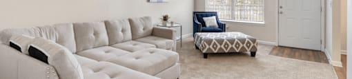 A living room with a white couch and a patterned ottoman.