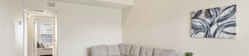 A living room with a grey sofa and a grey and white patterned ottoman.