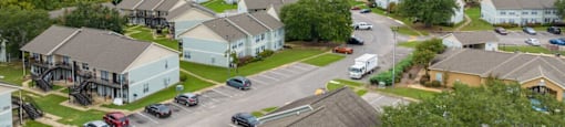 A view of a housing complex with a parking lot in the foreground.