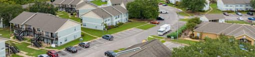 A view of a housing complex with a parking lot in the foreground.