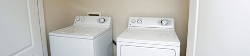 Two white washing machines in a small laundry room.