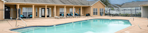 A large swimming pool in front of a building with a sunny sky.