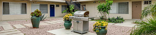 a courtyard with a grill and potted plants in front of a building