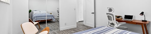 A bedroom with a bed, desk, and chair.