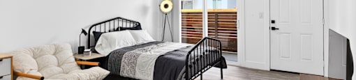 A bedroom with a bed, chair, and a window with blinds.