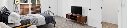 A bedroom with a bed, a bench, and a television.